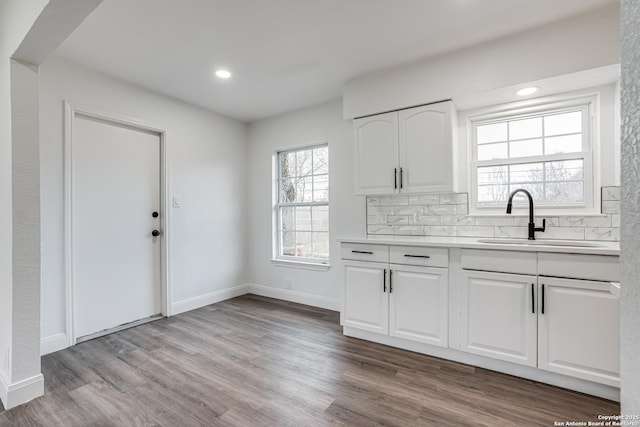 kitchen featuring sink, white cabinets, backsplash, and light hardwood / wood-style flooring