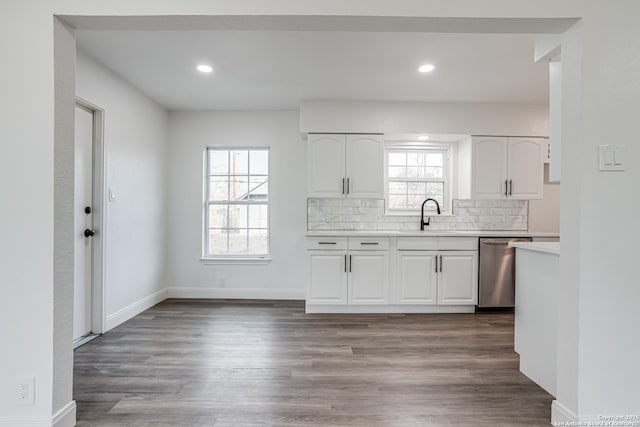 kitchen featuring sink, wood-type flooring, dishwasher, white cabinets, and backsplash