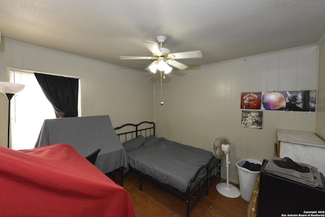 bedroom with ceiling fan, wood walls, dark hardwood / wood-style flooring, and a textured ceiling