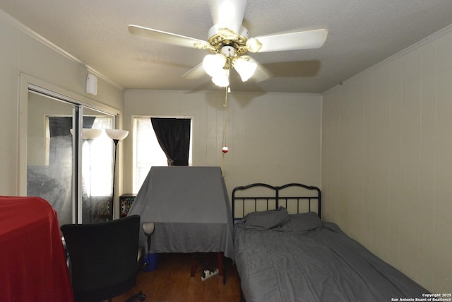 bedroom with dark hardwood / wood-style flooring, ceiling fan, crown molding, and wood walls