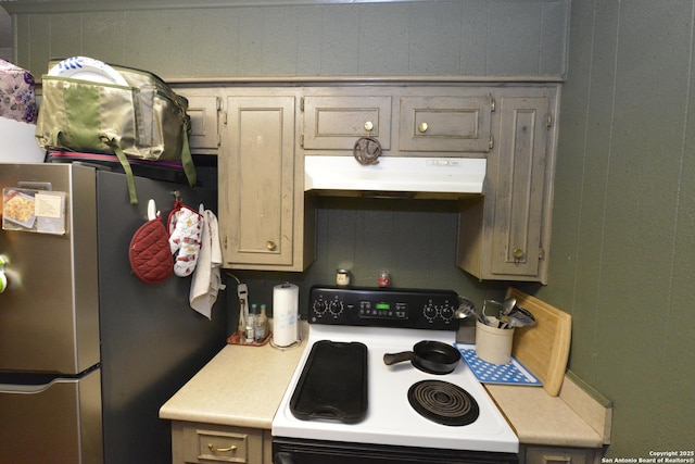 kitchen with stainless steel fridge, white range with electric stovetop, and wooden walls