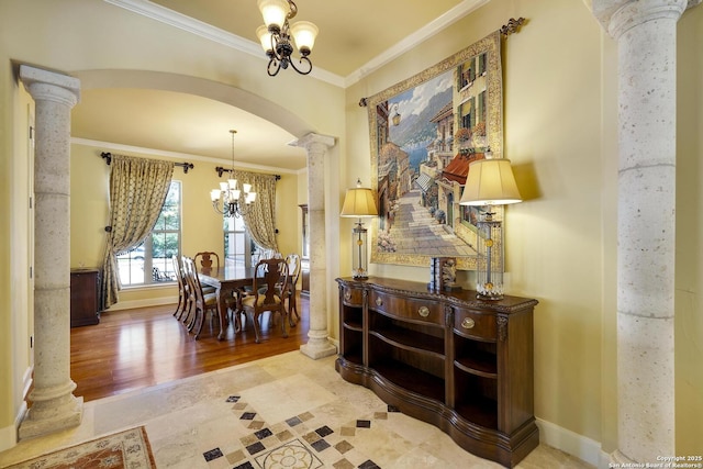 dining room with hardwood / wood-style floors, a notable chandelier, ornate columns, and crown molding