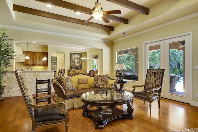 living area featuring a tray ceiling, crown molding, light hardwood / wood-style floors, and ceiling fan with notable chandelier