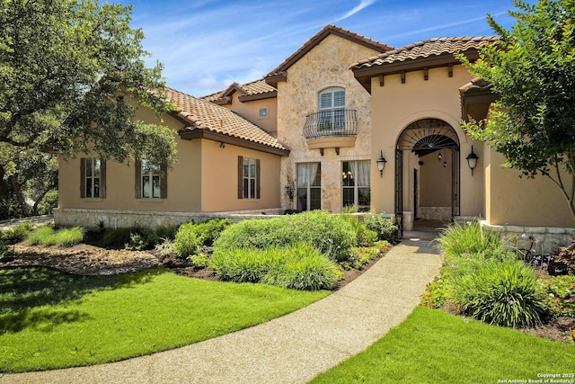 mediterranean / spanish-style home featuring a balcony and a front lawn