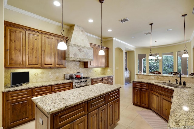 kitchen featuring light stone countertops, sink, pendant lighting, high end stainless steel range, and custom exhaust hood