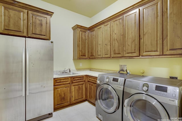 clothes washing area featuring cabinets, sink, and washer and dryer