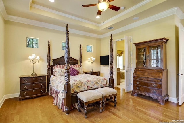 bedroom featuring ceiling fan, ornamental molding, light hardwood / wood-style flooring, and a tray ceiling