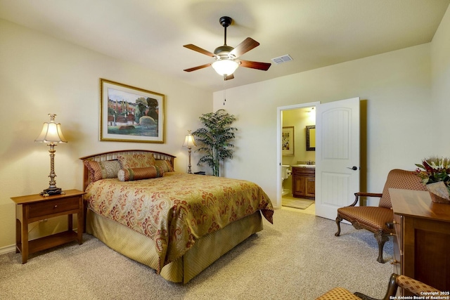 carpeted bedroom with ensuite bathroom and ceiling fan