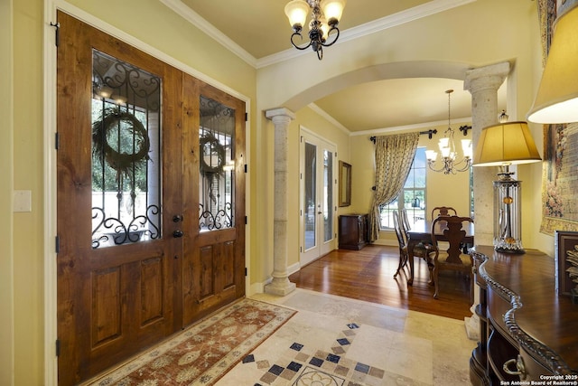 entrance foyer featuring french doors, an inviting chandelier, ornamental molding, and ornate columns