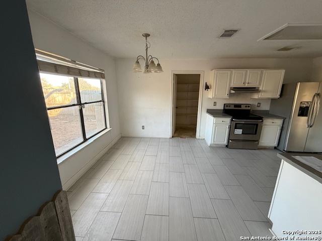 kitchen with appliances with stainless steel finishes, a textured ceiling, decorative light fixtures, an inviting chandelier, and white cabinets