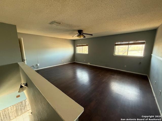 unfurnished room featuring ceiling fan, dark hardwood / wood-style flooring, and a textured ceiling