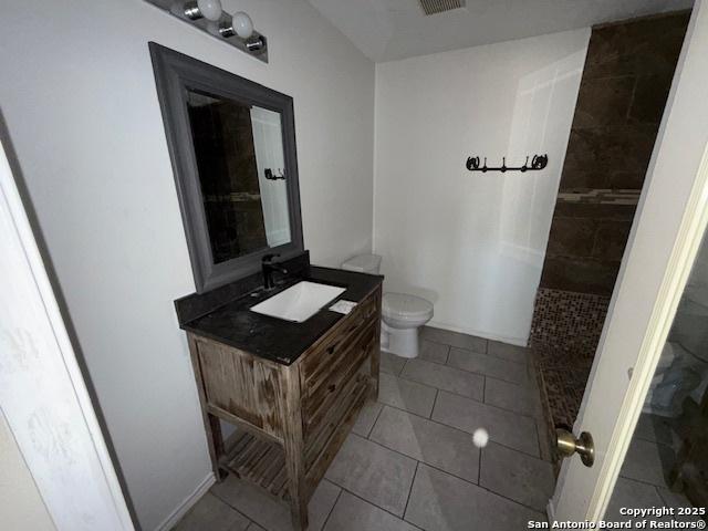 bathroom with tile patterned floors, toilet, a shower, and vanity