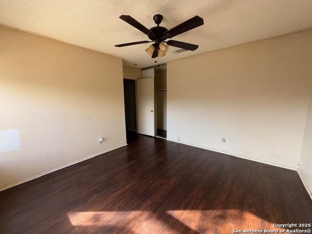 unfurnished room with a textured ceiling, ceiling fan, and dark wood-type flooring