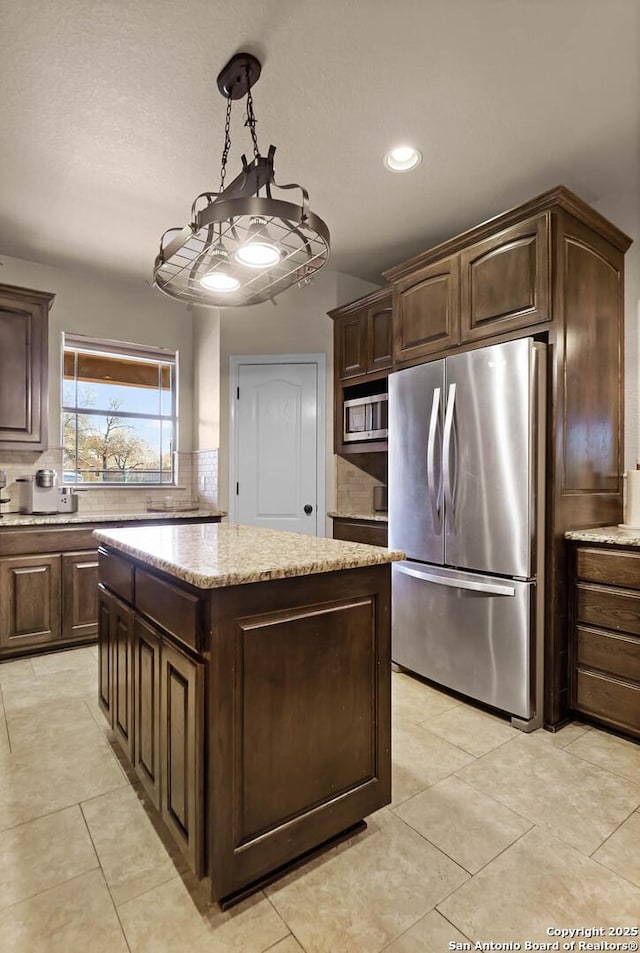 kitchen with dark brown cabinetry, a center island, hanging light fixtures, and appliances with stainless steel finishes