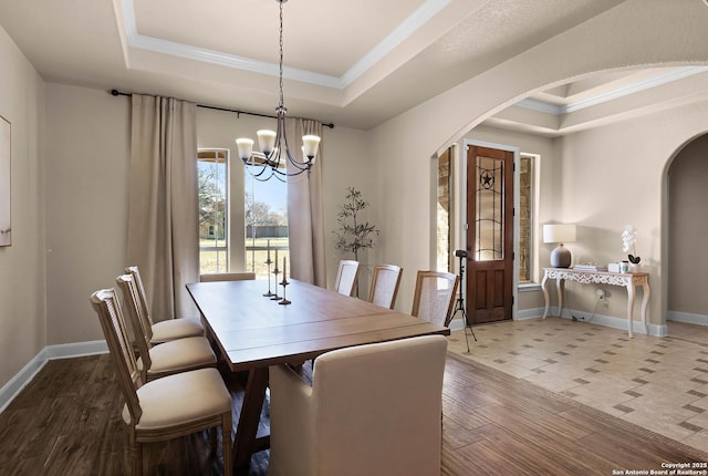 dining space featuring a raised ceiling, ornamental molding, and a notable chandelier