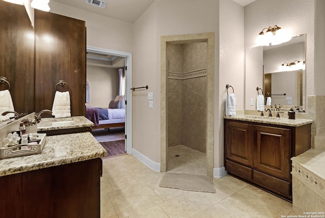 bathroom featuring tile patterned flooring, vanity, and tiled shower