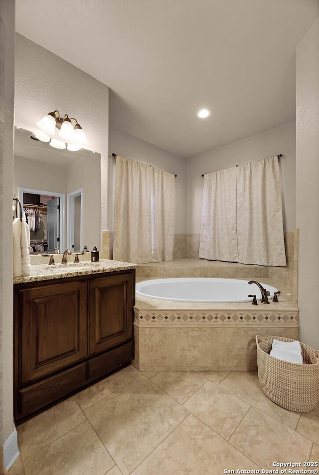 bathroom with tile patterned flooring, vanity, and a relaxing tiled tub