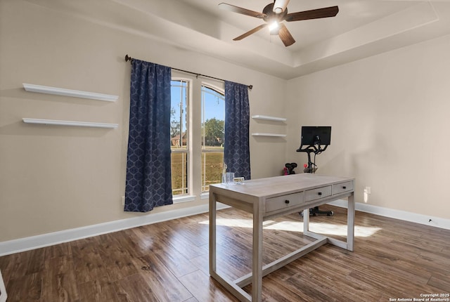 home office featuring hardwood / wood-style floors, plenty of natural light, ceiling fan, and a raised ceiling