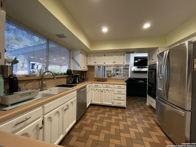 kitchen with appliances with stainless steel finishes, kitchen peninsula, sink, and white cabinets