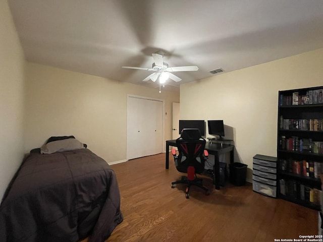 bedroom with dark hardwood / wood-style flooring, a closet, and ceiling fan