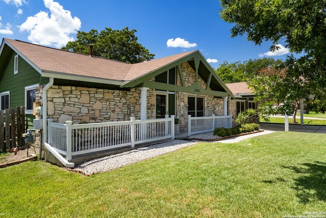 rear view of property featuring a lawn and covered porch