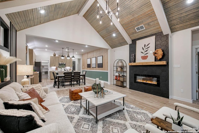 living room with a fireplace, an inviting chandelier, high vaulted ceiling, and beamed ceiling