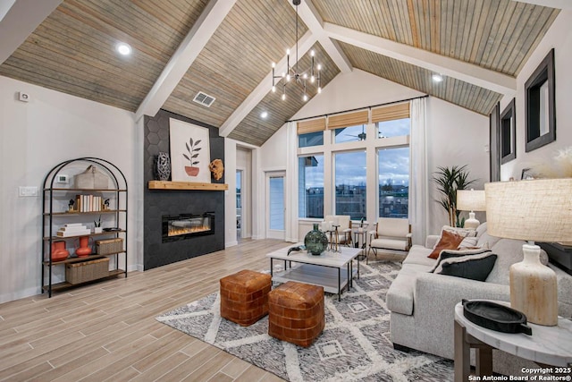 living room featuring beamed ceiling, a notable chandelier, a large fireplace, and high vaulted ceiling