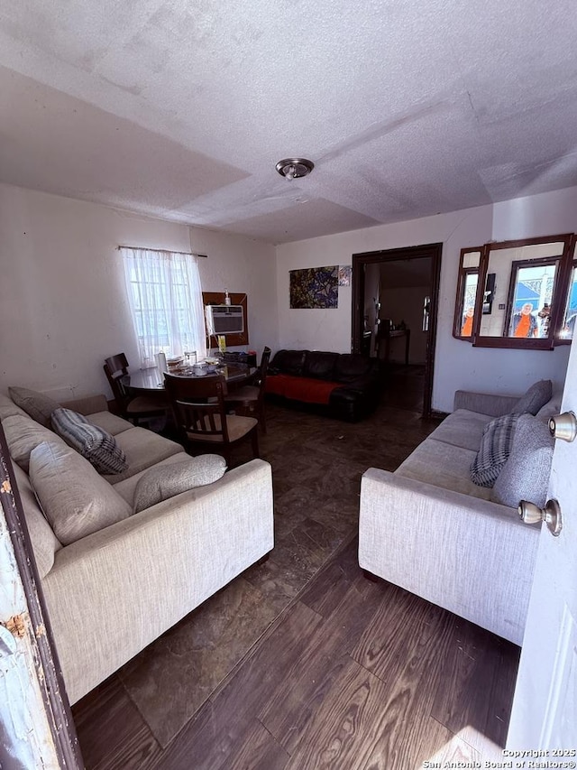 living room with a textured ceiling, dark hardwood / wood-style floors, and an AC wall unit