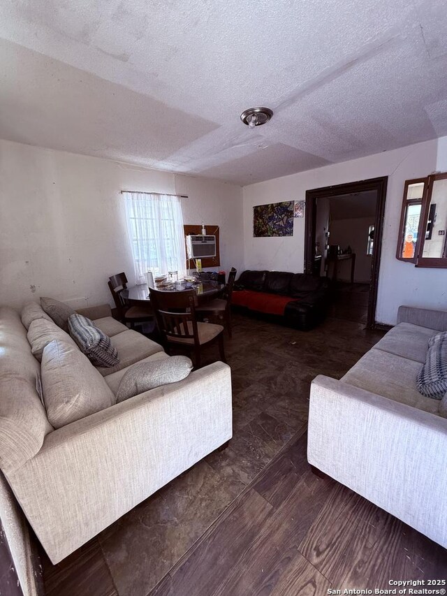 living room featuring dark hardwood / wood-style flooring, a textured ceiling, and an AC wall unit