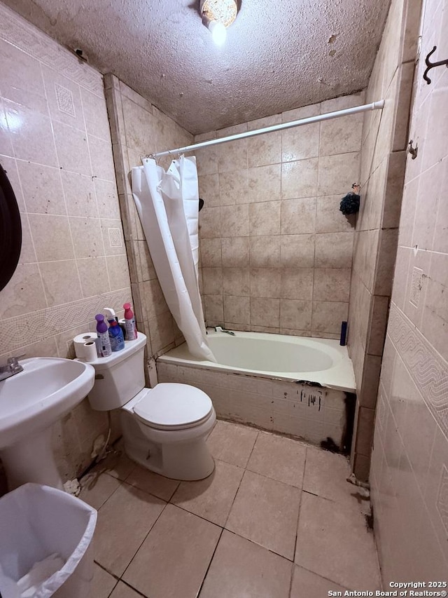 bathroom featuring a textured ceiling, tile patterned floors, tile walls, and shower / tub combo with curtain