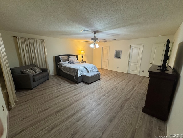 bedroom featuring ceiling fan, wood-type flooring, and a textured ceiling