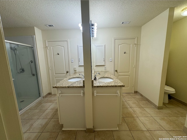 bathroom featuring tile patterned flooring, vanity, toilet, and a shower with shower door