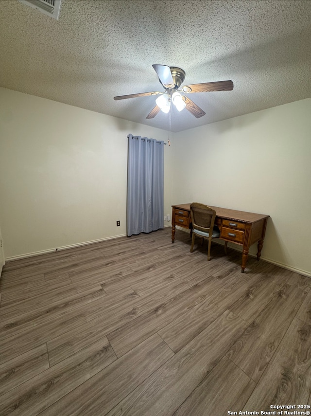 empty room with a textured ceiling, hardwood / wood-style flooring, and ceiling fan