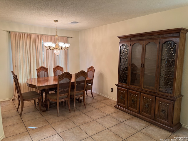 dining area with a notable chandelier, light tile patterned flooring, and a textured ceiling