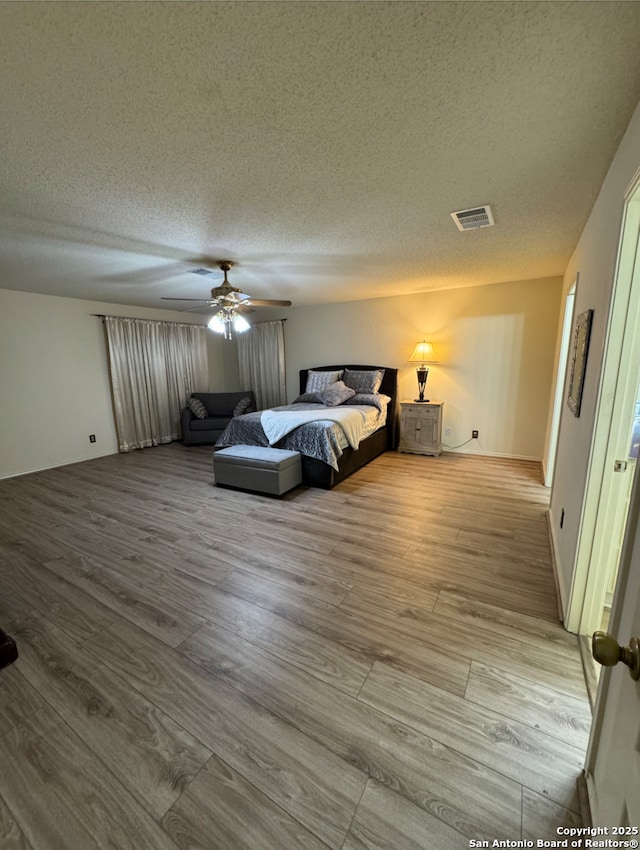 bedroom featuring a textured ceiling, light wood-type flooring, and ceiling fan