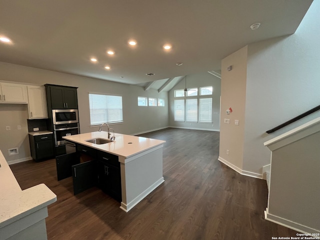 kitchen featuring sink, stainless steel appliances, dark hardwood / wood-style flooring, lofted ceiling, and a kitchen island with sink