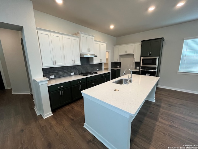 kitchen featuring a center island with sink, sink, appliances with stainless steel finishes, dark hardwood / wood-style flooring, and white cabinetry