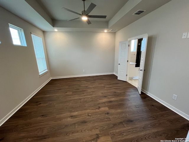 unfurnished room featuring a tray ceiling, ceiling fan, and dark hardwood / wood-style flooring