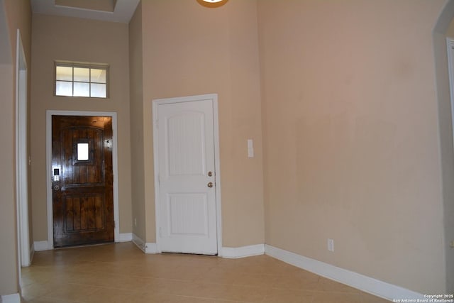 foyer entrance with light tile patterned floors and a high ceiling