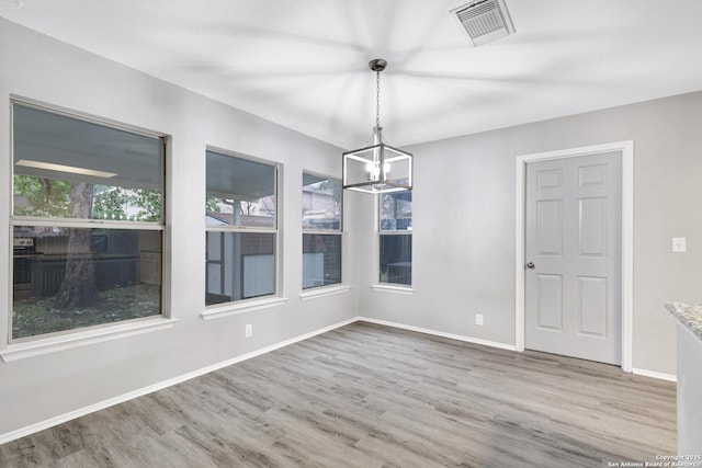 unfurnished dining area featuring hardwood / wood-style floors and an inviting chandelier