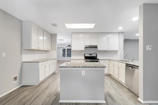 kitchen featuring white cabinets, sink, a skylight, appliances with stainless steel finishes, and kitchen peninsula