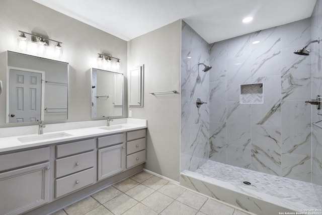 bathroom with tiled shower, vanity, and tile patterned flooring