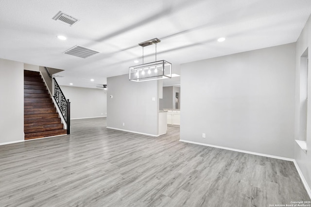 unfurnished living room featuring ceiling fan, light wood-type flooring, and a textured ceiling