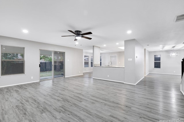 unfurnished living room featuring hardwood / wood-style floors, ceiling fan, and sink