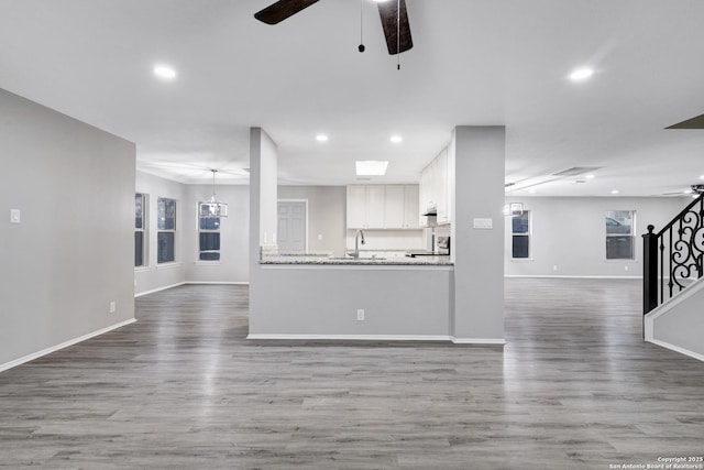 unfurnished living room featuring wood-type flooring, ceiling fan, and sink