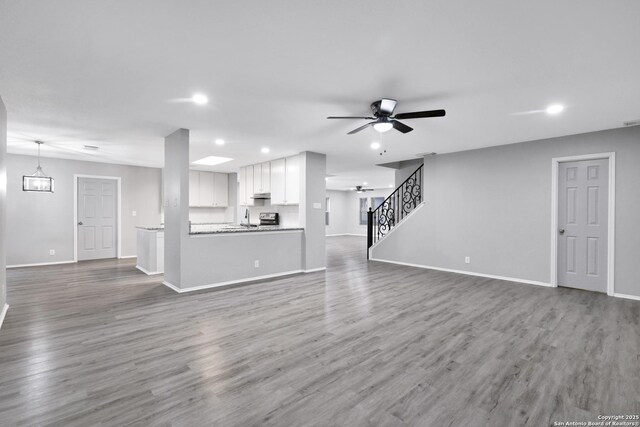 unfurnished living room featuring ceiling fan, sink, and dark hardwood / wood-style floors