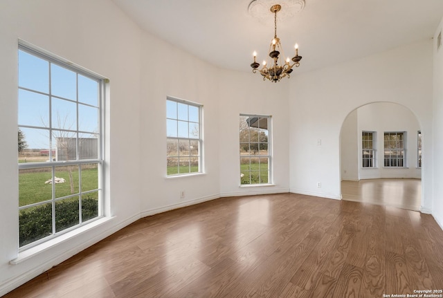 spare room with a chandelier and wood-type flooring