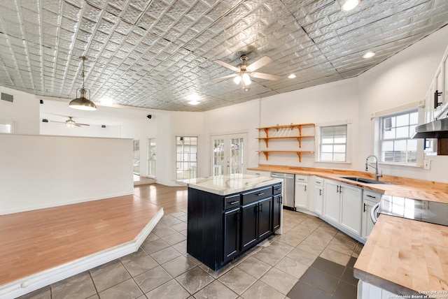 kitchen featuring brick ceiling, butcher block countertops, white cabinets, and a center island