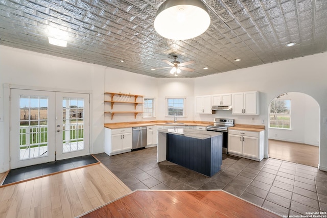 kitchen with appliances with stainless steel finishes, white cabinetry, french doors, and brick ceiling