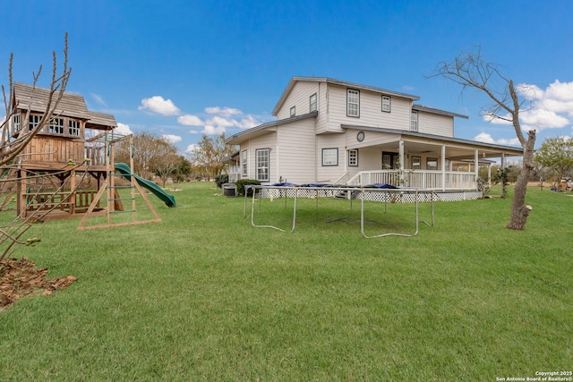 rear view of house with a playground, a trampoline, and a yard